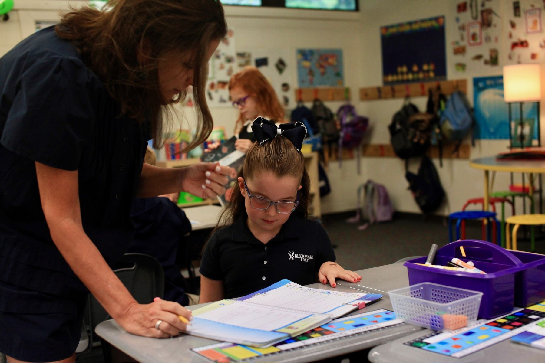 A teacher helping a student with her work at her desk