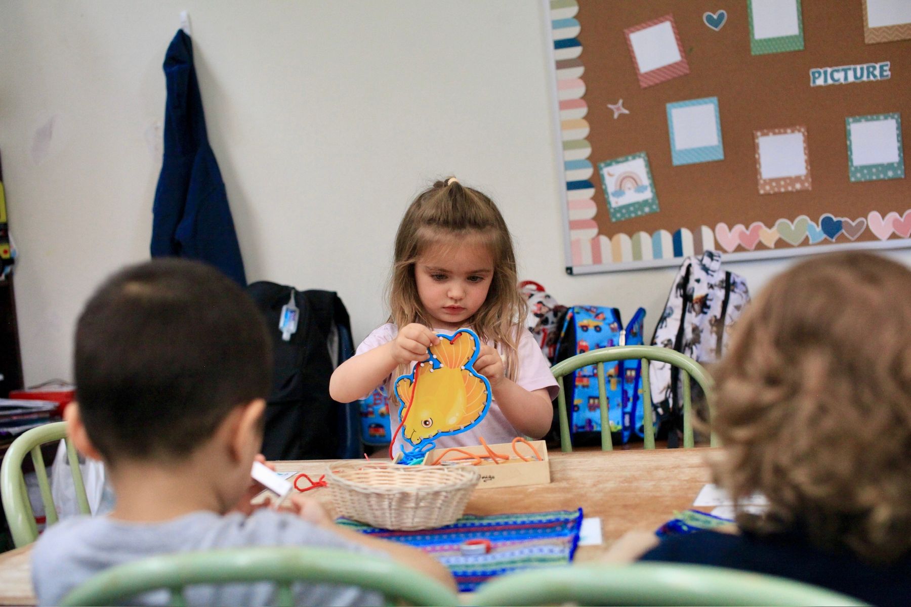 A Primary student concentrating on a lacing card
