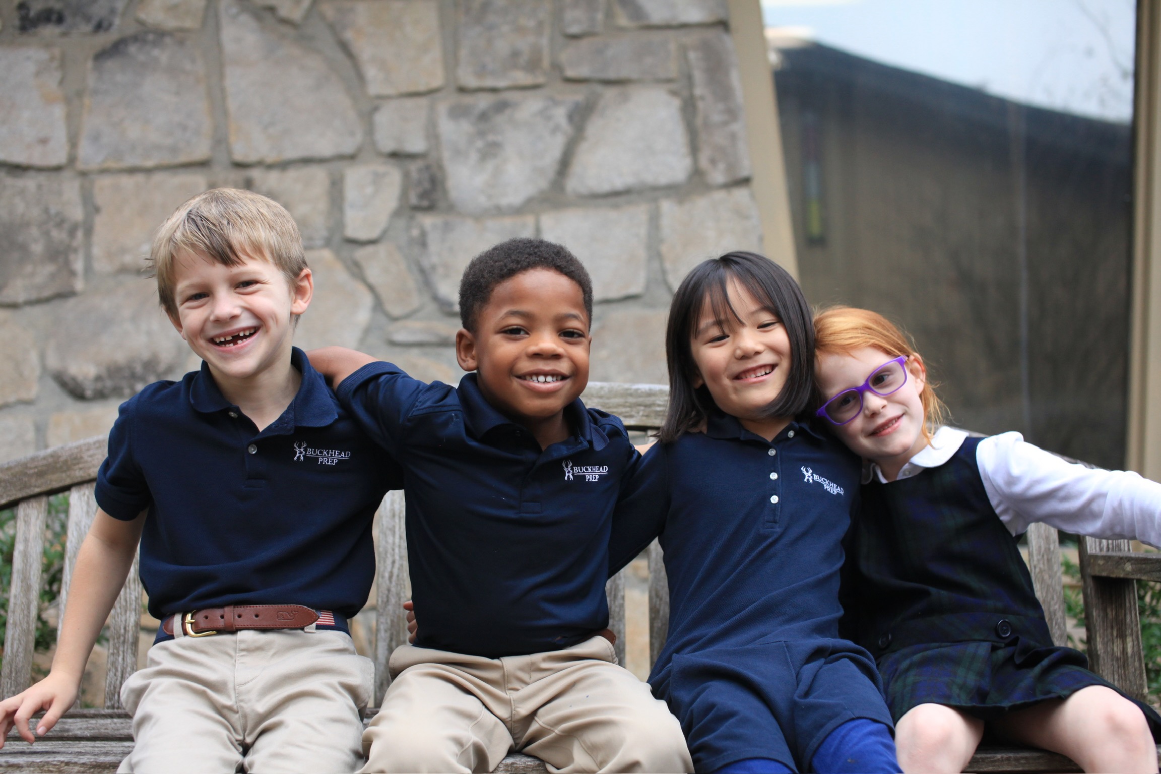 Four Buckhead Prep students smiling together outside