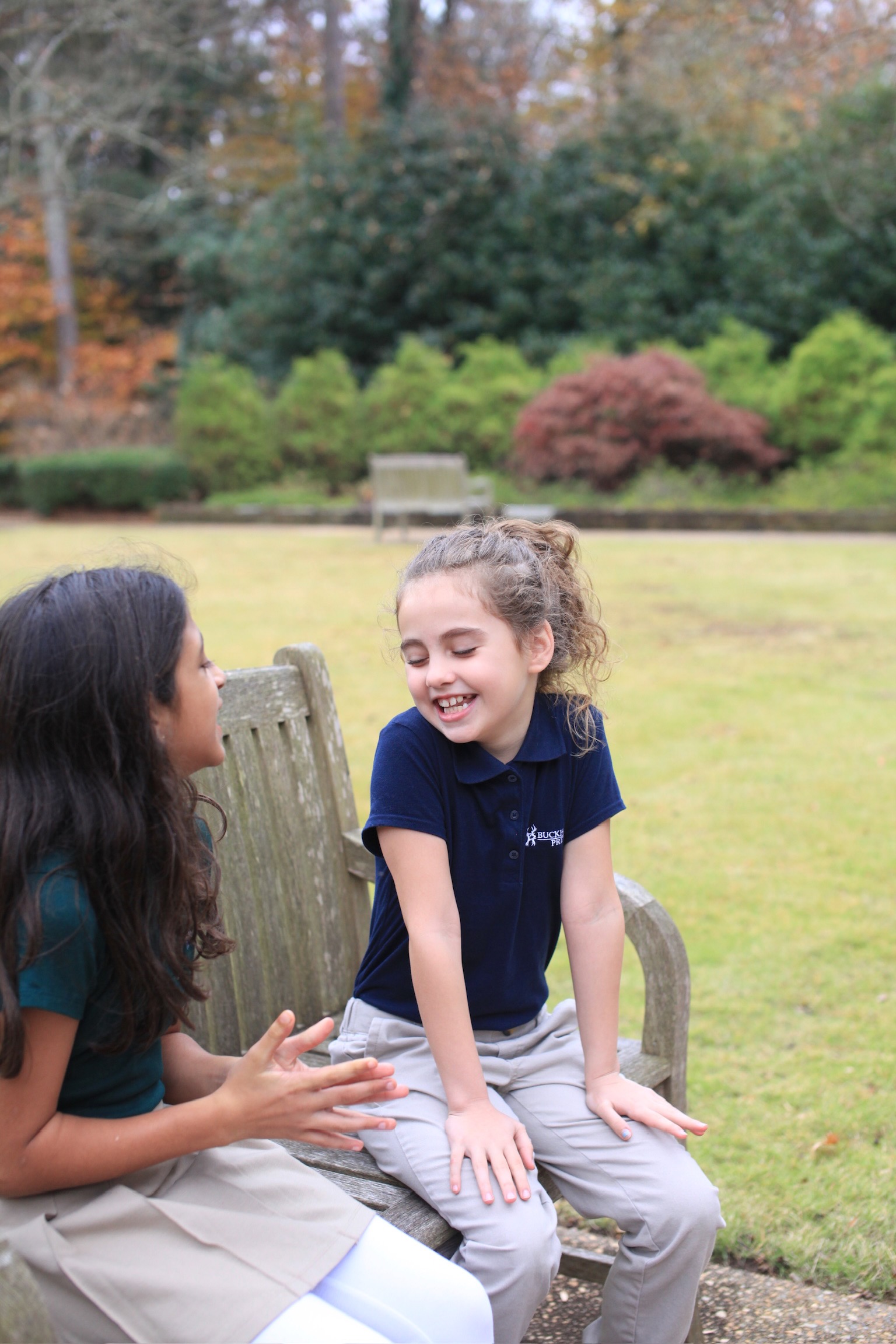 Two students laughing together on the lawn